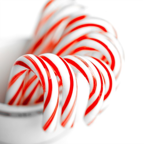 White and red peppermint candy canes in bucket on white background.