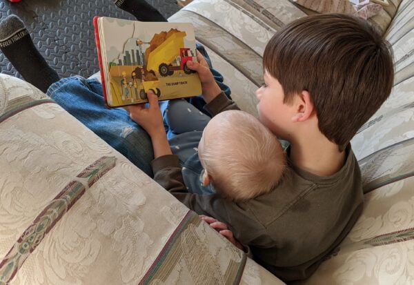 big brother reading to baby